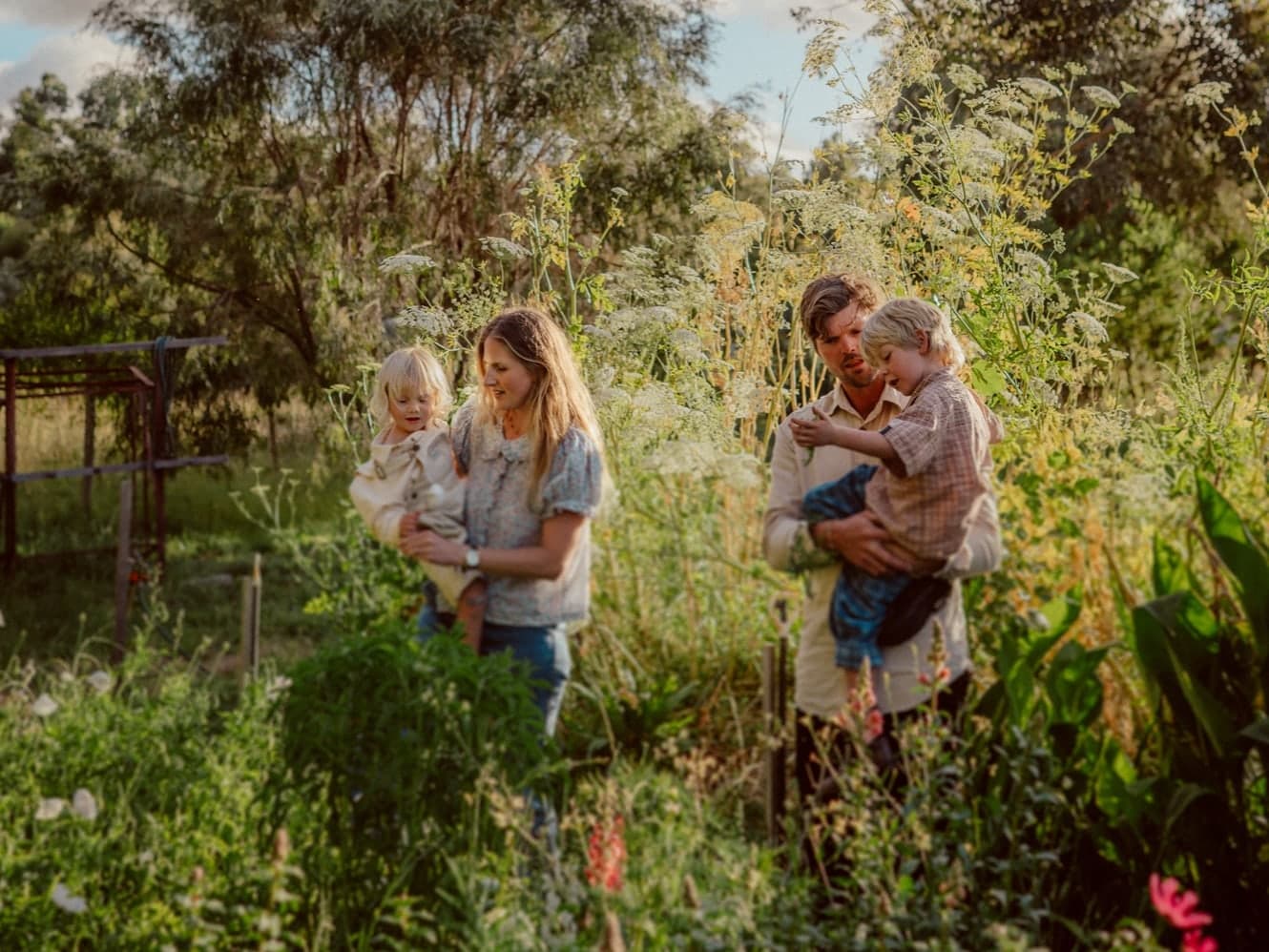 Grace and David carrying their two children through the garden beds.