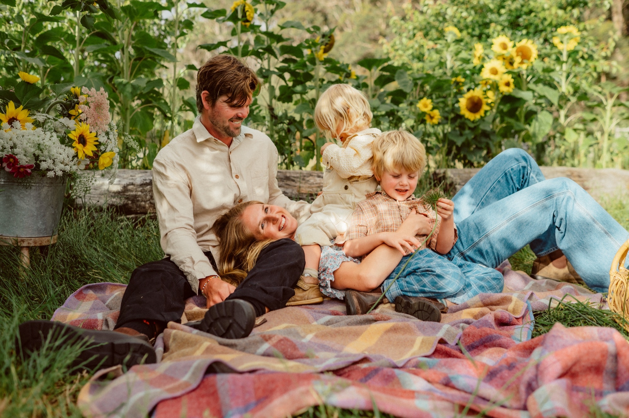 The family laughing together on a picnic blanket at the farm.