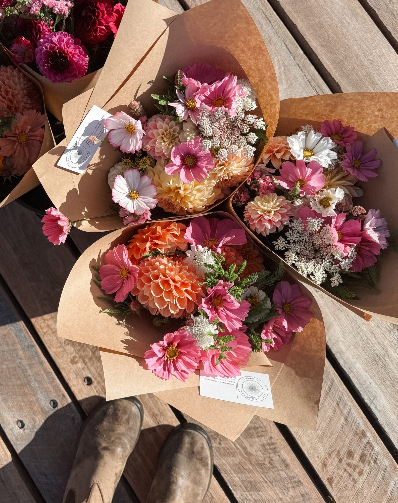 Hand-tied bouquets wrapped in kraft paper, laid out on the timber bench.