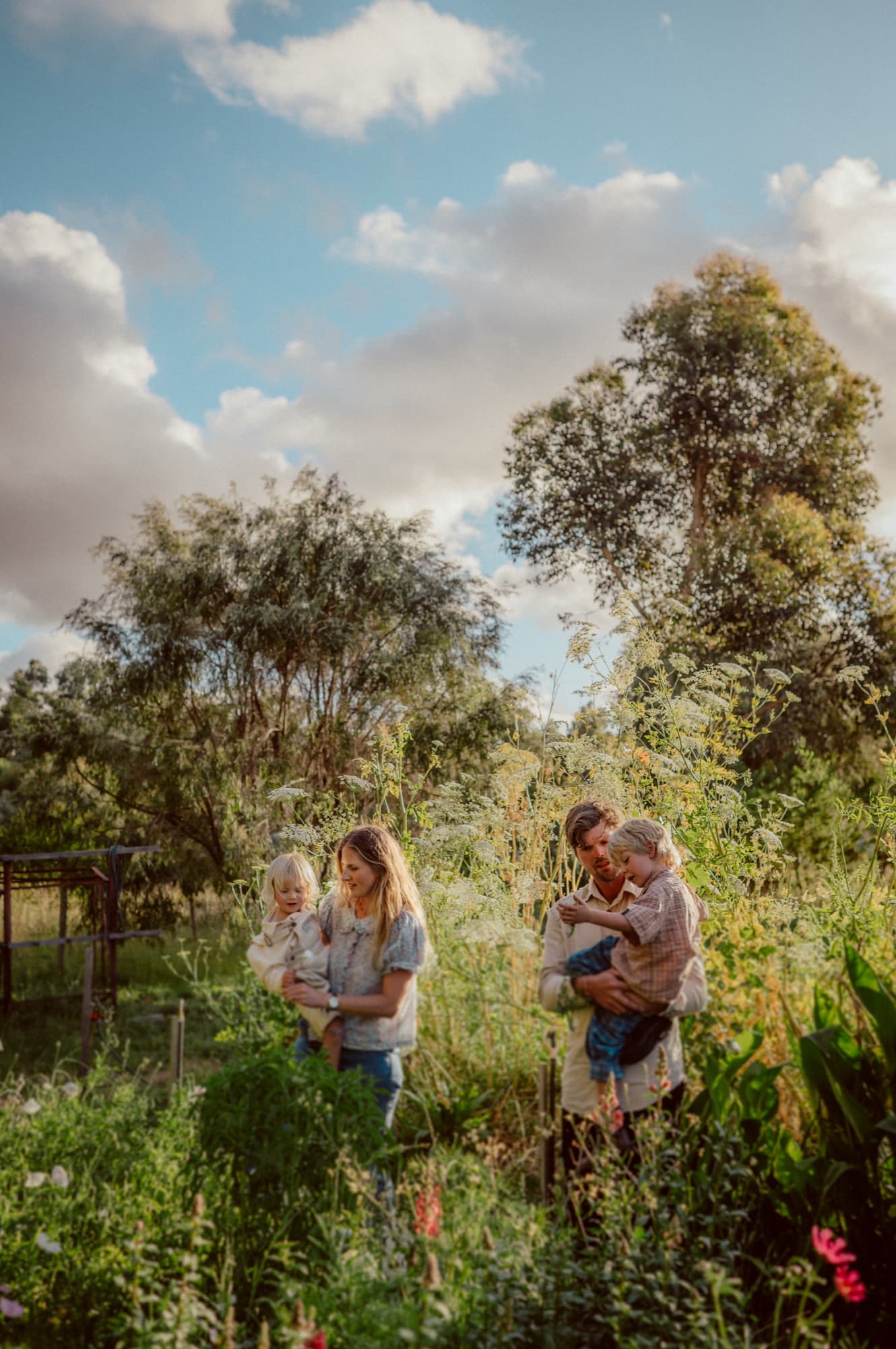 Grace and David carrying their two children through the garden beds.
