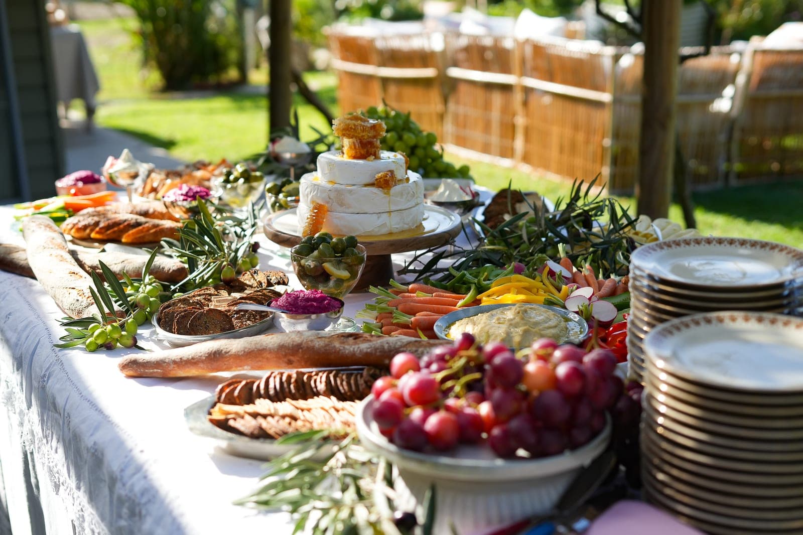 A grazing table with a cheese tier, honeycomb, olives and fruit.